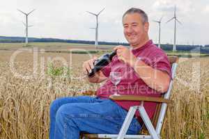 Man sitting with wine bottle in cornfield