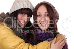 Zwei junge Frauen im Winter umarmen sich