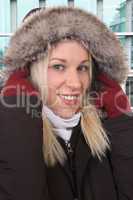 Lachende Frau im Winter mit warmer Jacke draußen in der Stadt