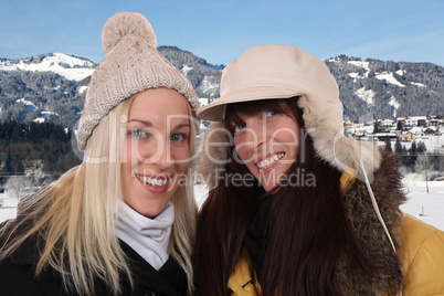 Zwei lachende Frauen machen Urlaub in den Bergen im Winter