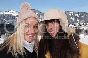 Zwei lachende Frauen machen Urlaub in den Bergen im Winter