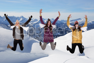 Junge Frauen springen im Winter in den Bergen im Schnee