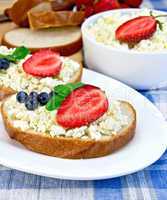 Bread with curd and berries on blue cloth