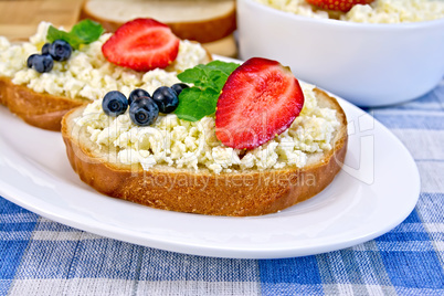 Bread with curd and berries on blue checkered cloth