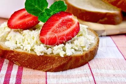 Bread with curd and strawberries on red fabric