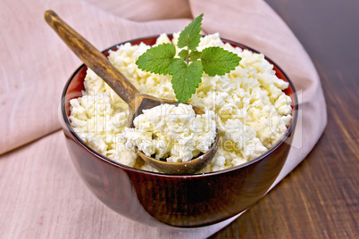 Curd in wooden bowl with spoon and mint on board