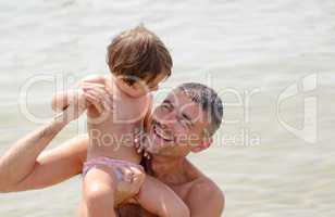 Baby playing with father in the sea water