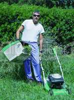 Man mowing overgrown lawn in his yard