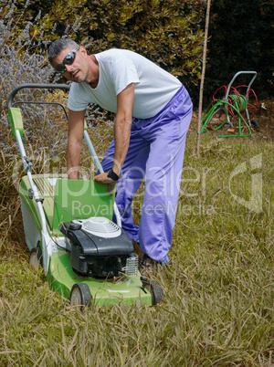 Man mowing overgrown lawn in his yard