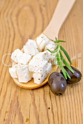 Feta in wooden spoon with olives on board