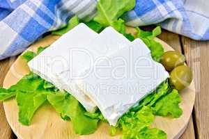 Feta with olives and lettuce on board with blue cloth