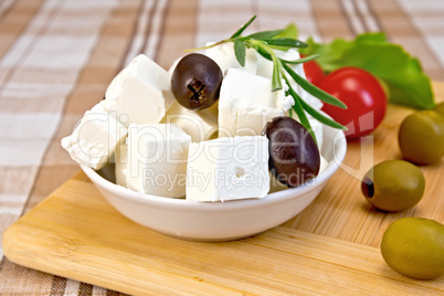 Feta with olives in cup on brown cloth and board