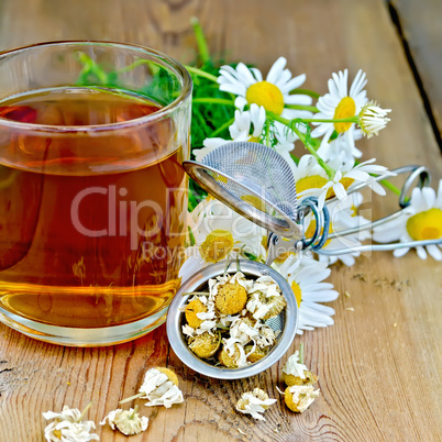 Herbal chamomile tea in mug with strainer on board