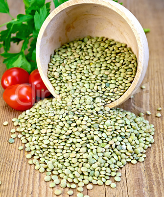 Lentils green in bowl with tomatoes on board