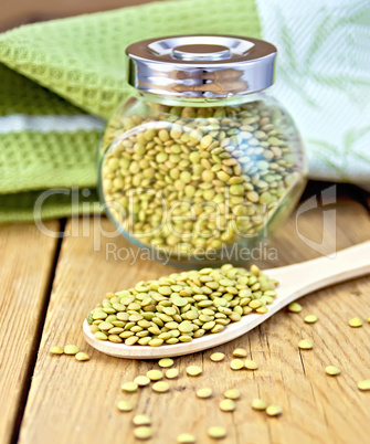 Lentils green in jar and spoon with napkin on board