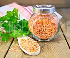 Lentils red in jar and spoon with parsley on board
