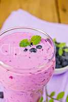 Milkshake with blueberries in glass on board