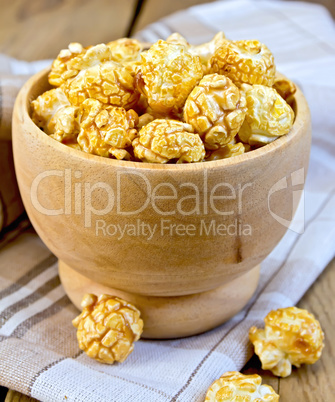 Popcorn caramel in wooden bowl on board with napkin