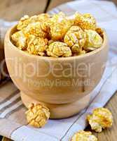 Popcorn caramel in wooden bowl on board with napkin