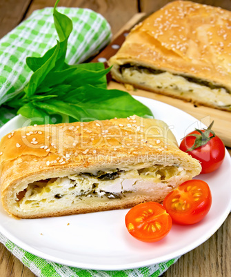 Roll filled with spinach and cheese on board with tomatoes