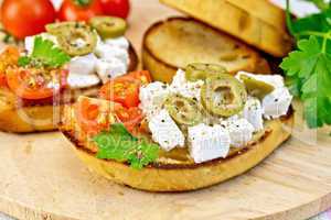 Sandwich with feta and olives on wooden board