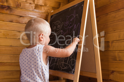 Little boy drawing with chalk on a blackboard