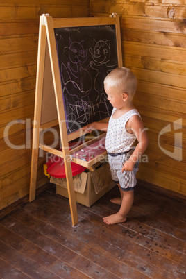 Little boy drawing with chalk on a blackboard