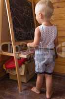 Little boy drawing with chalk on a blackboard