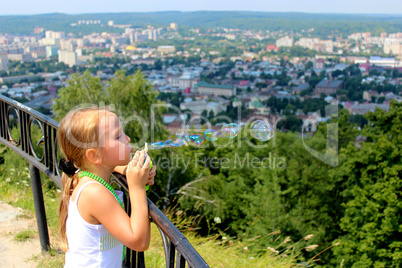 little girl swelling soap bubbles out of city
