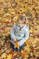 little girl with yellow leaves in the park