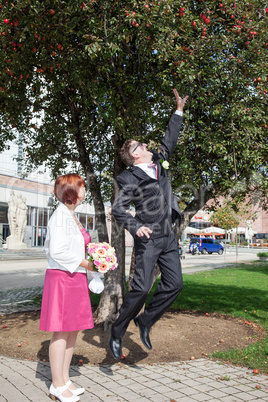 Groom tries to pick apple from the tree