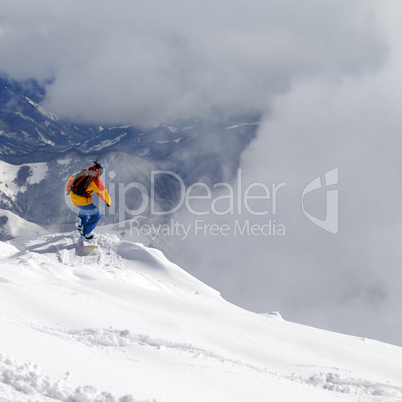 Snowboarder on off-piste slope an mountains in mist