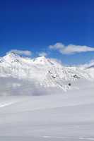 Winter snowy mountains and ski slope at nice day.