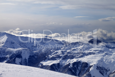 Winter mountains in clouds and ski slope