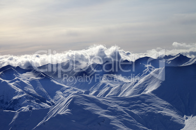 Evening snowy mountains in mist and sunlight clouds