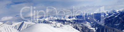 Panorama of off-piste snowy slope and cloudy mountains