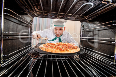 Chef cooking pizza in the oven.