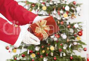 Santa Claus with gift front of tree