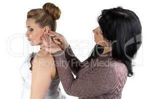 Bridesmade helping bride to wear earrings