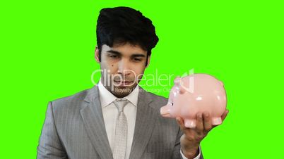 Young businessman inserting money into a piggy bank