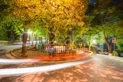 Car light trails at night on a downhill road