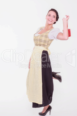 Junge bayerische Frau im Dirndl hält ein kleines Päckchen mit dem Finger über der Schulter