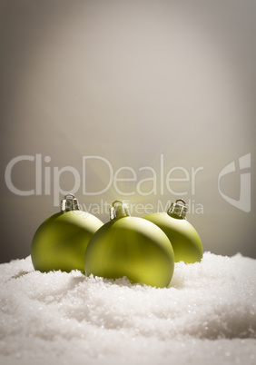 Green Christmas Ornaments on Snow Over a Grey Background