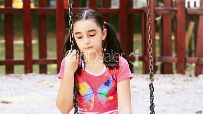 Sad young girl sits on swing