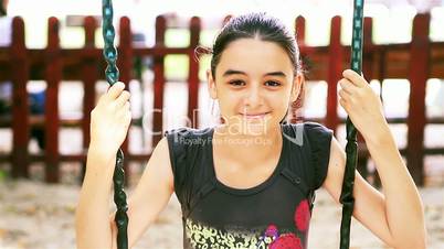 Teenage girl on swing smiling at camera