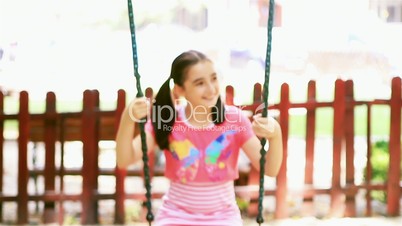 Little girl swinging in summer park