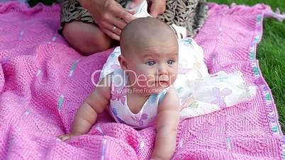 happy smiling cheerful baby girl on pink blanket in park