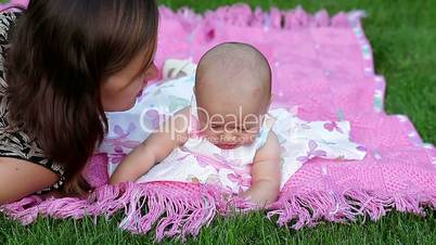 happy smiling cheerful baby girl on pink blanket in park