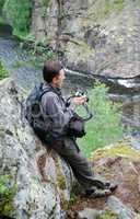 Man with camera on the rock over mountain river.