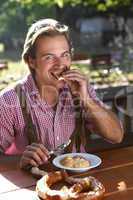 Attractive man eats traditional cheese with pretzel in a Bavaria